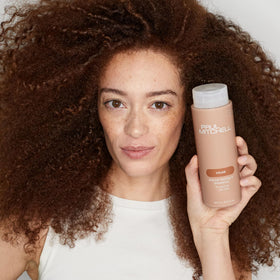 Paul Mitchell 16.9 fl oz bottle next to common items for scale and travel-friendly size benefit