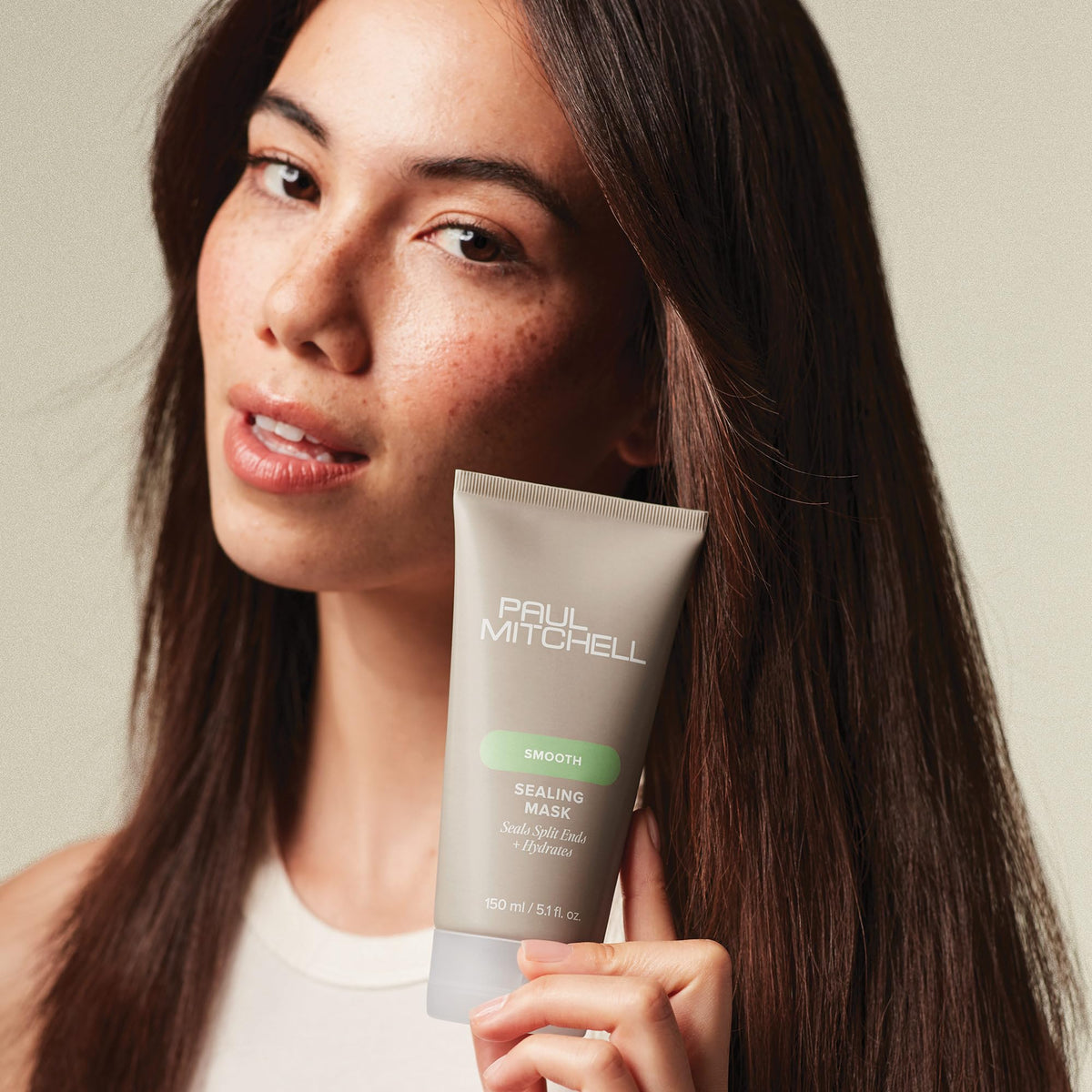 Hand holding Paul Mitchell sealing mask jar to show scale and portability benefit