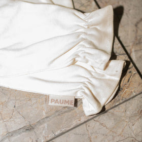 PAUME gloves on nightstand next to moisturizer for nightly routine