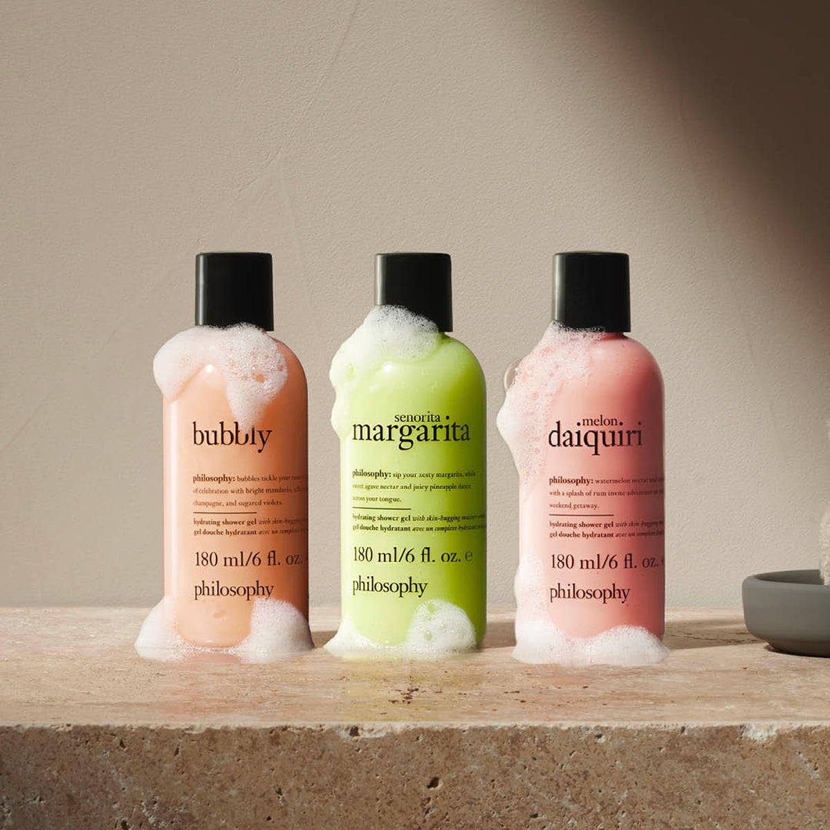 philosophy travel-size bottles next to a hand showing compact travel convenience