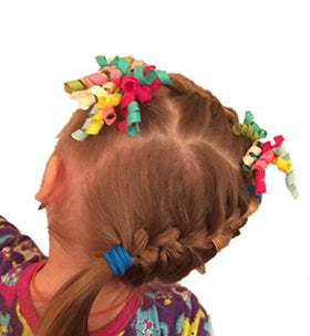 PIDOUDOU lifestyle image of smiling girl wearing mixed-color bows showing outfit coordination benefit