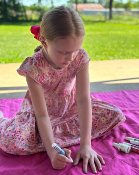Piggy Paint pen beside crayon for scale showing compact kid-friendly size