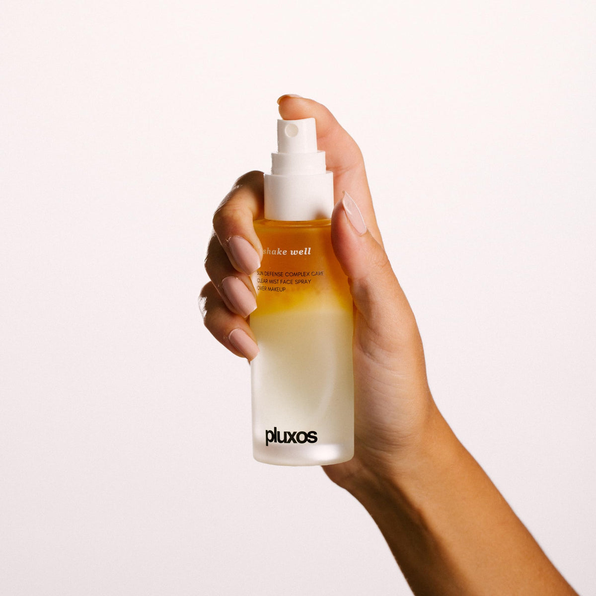 PLUXOS mist being sprayed onto face demonstrating quick reapplication benefit