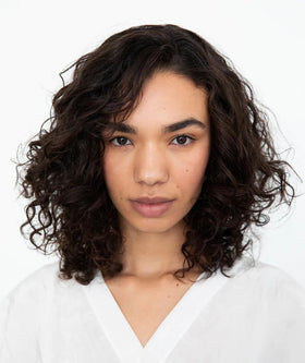 R+Co Cassette in bathroom lifestyle with curls styled showing defined bounce