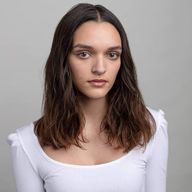 R+Co applying balm to damp hair to show frizz control and styling ease