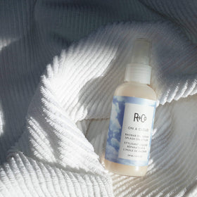 R+Co bottle in hand to show size and coverage benefit for travel-friendly styling