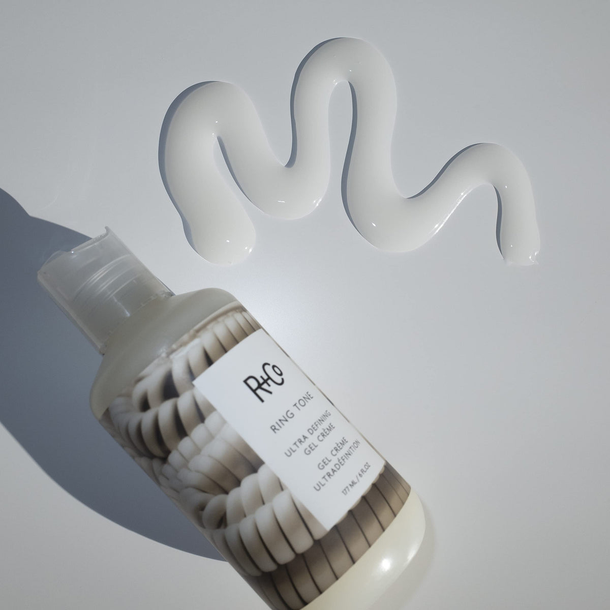 R+Co Ring Tone on a bathroom counter with greenery, suggesting daily styling ritual