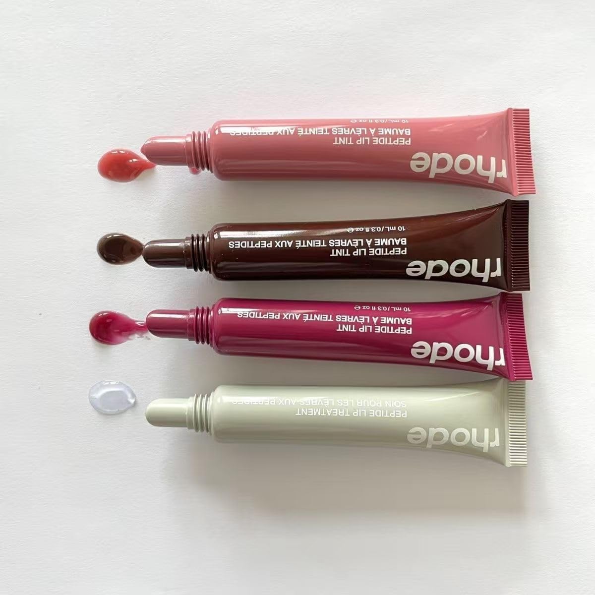 Rhode gloss lip tint tube in hand showing compact travel-friendly size