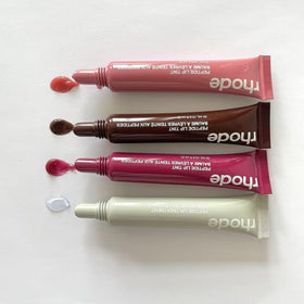 Rhode gloss lip tint tube in hand showing compact travel-friendly size