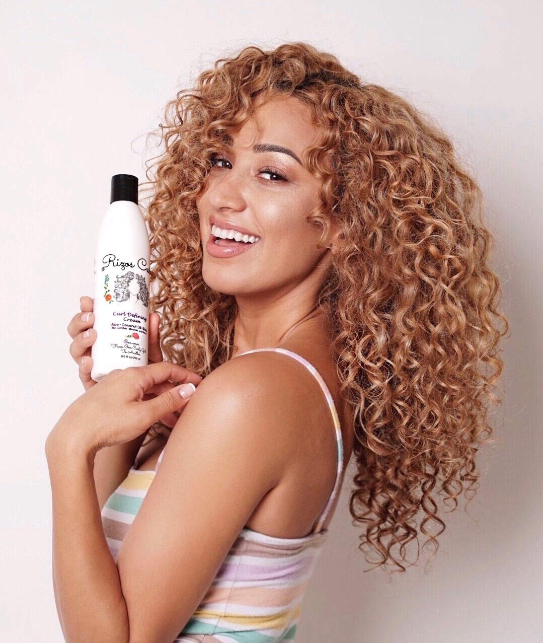 Rizos Curls bottle in hand showing 10 fl oz scale and travel convenience