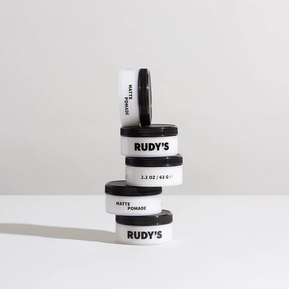 Rudy's pomade next to a coin illustrating 2.2 oz size and portable convenience