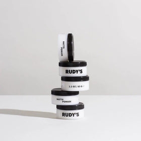 Rudy's pomade next to a coin illustrating 2.2 oz size and portable convenience
