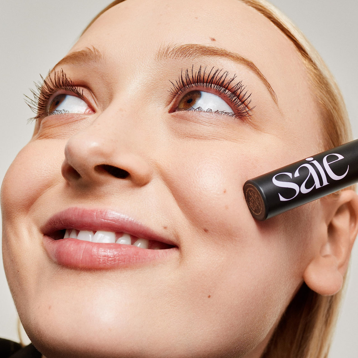 Saie mascara 101 on model closeup showing lifted brown lashes and natural finish