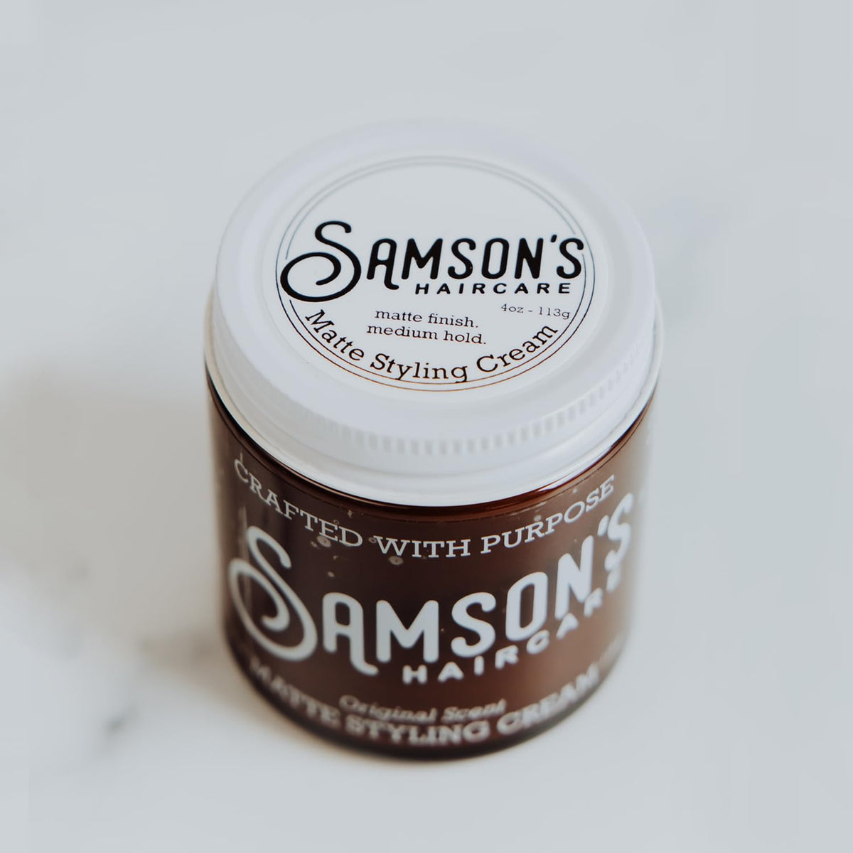 SAMSON'S HAIRCARE cream on hands being applied for effortless styling benefit