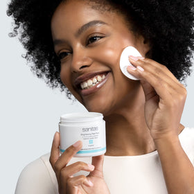 Sanitas pad in hand applying to cheek to demonstrate gentle, precise use