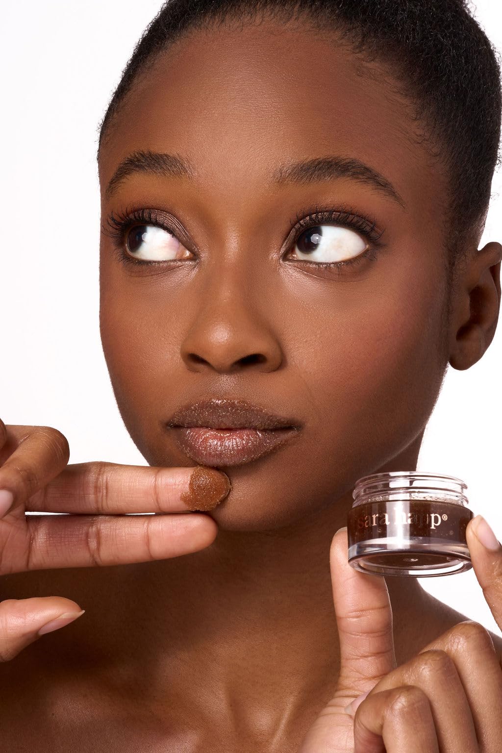 Sara Happ applying scrub to lips demonstrating gentle massage and instant smoothing benefit