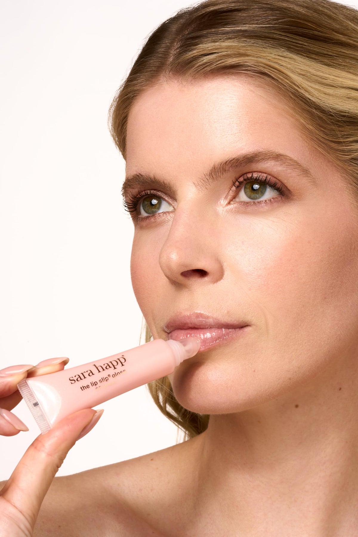 Sara Happ gloss layered over lipstick showing amplified shine and color boost benefit