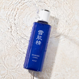 Hands applying SEKKISEI lotion demonstrating easy layering and absorption