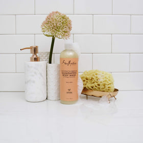 Shea Moisture bottle next to common objects to show 13-ounce size and travel-friendly benefit