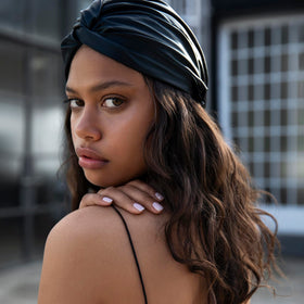 Model wearing SLIP black turban in bedroom showing overnight hair protection