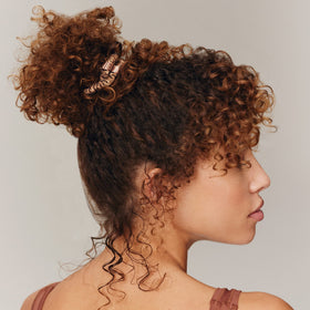 Slip scrunchie on model ponytail, creates sleek low-bulk hairstyle