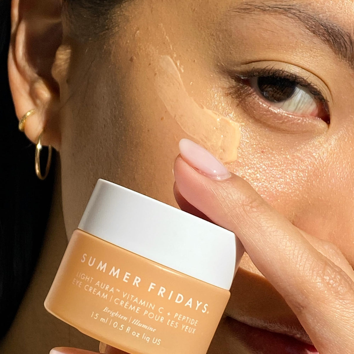 Summer Fridays applying eye cream under eye to brighten and hydrate