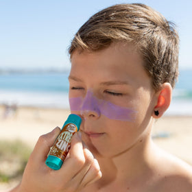 Sun Zapper stick next to a hand showing 15g scale for travel-friendly portability