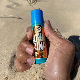 Sun Zapper stick held in hand to show 15g size and portability benefit