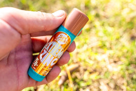Sun Zapper stick beside surfboard pouch showing portable 15g size