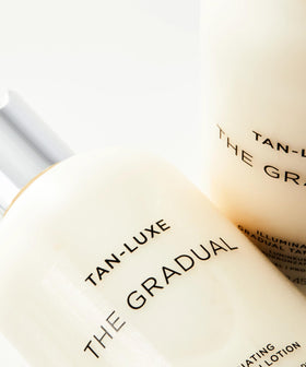 TAN-LUXE bottle in hand for size comparison illustrating 100 ml portability