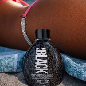 TANNING PARADISE bottle beside a hand for 13.5oz size reference and travel practicality