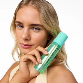 Tanologist bottle beside passport and sunscreen to show travel-ready convenience and no-transfer benefit