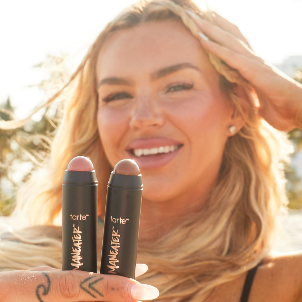tarte maneater stick in hand size comparison illustrates portable, on-the-go use