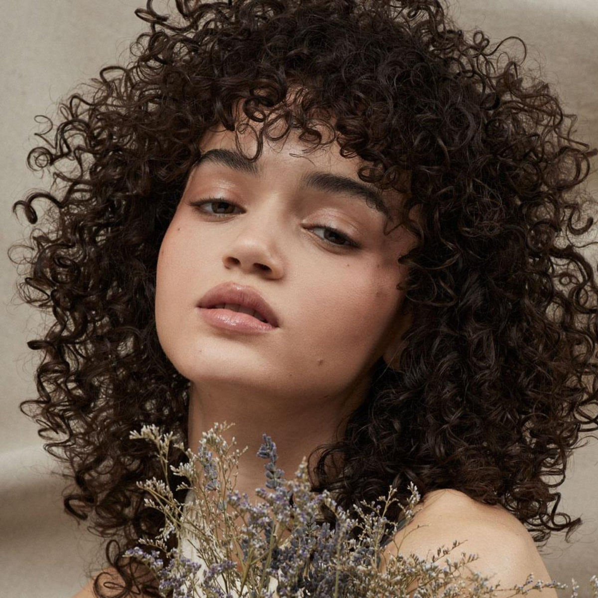 Model applying Tea Tree cowash to curly hair for detangling benefit