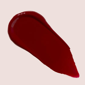 The Lip Bar Gamechanger gloss swatch on hand showing sheer nude glow