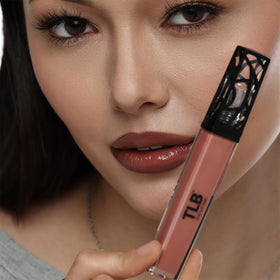 Bottles of argan and olive oil near The Lip Bar gloss highlighting moisturizing benefits