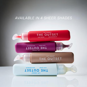 The Outset placed on a vanity beside lipstick showing layering over makeup