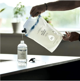 The Unscented Company pouring refill into pump bottle for economical refill