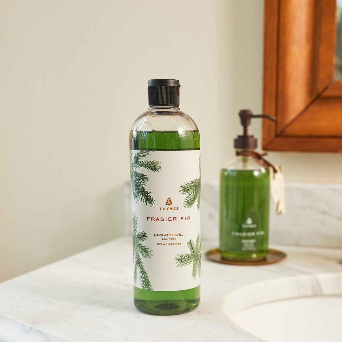 Thymes Frasier Fir pouring refill into dispenser portraying easy refill benefit