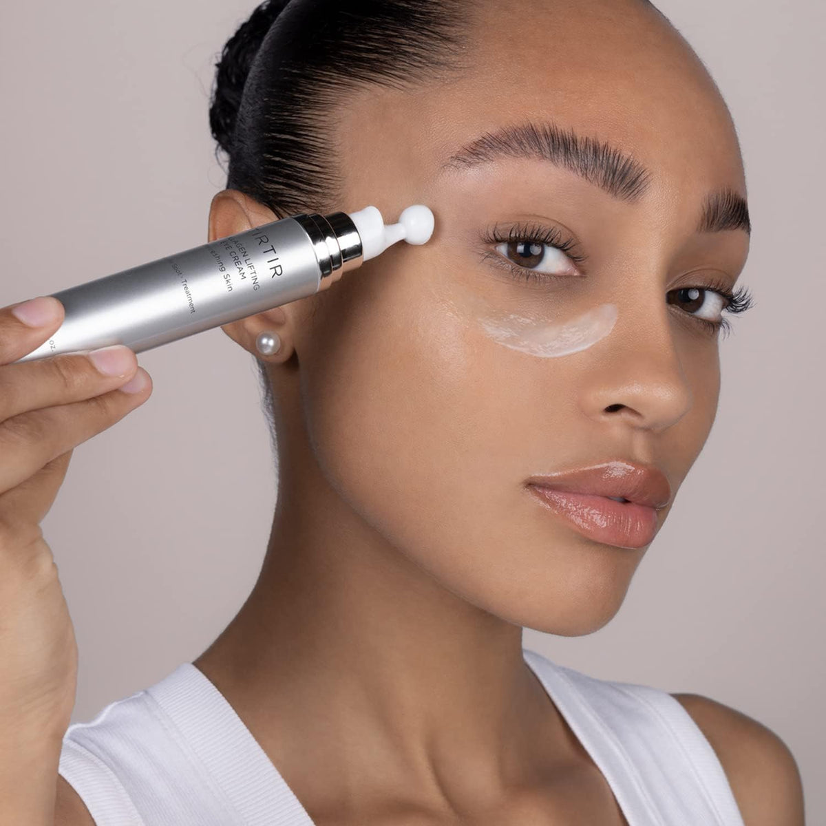 Model applying TIRTIR under-eye with roller to reduce puffiness and smooth skin