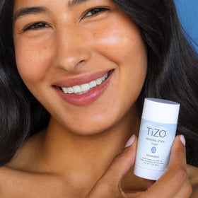 TIZO mineral stick being applied to cheek for quick on-the-go protection