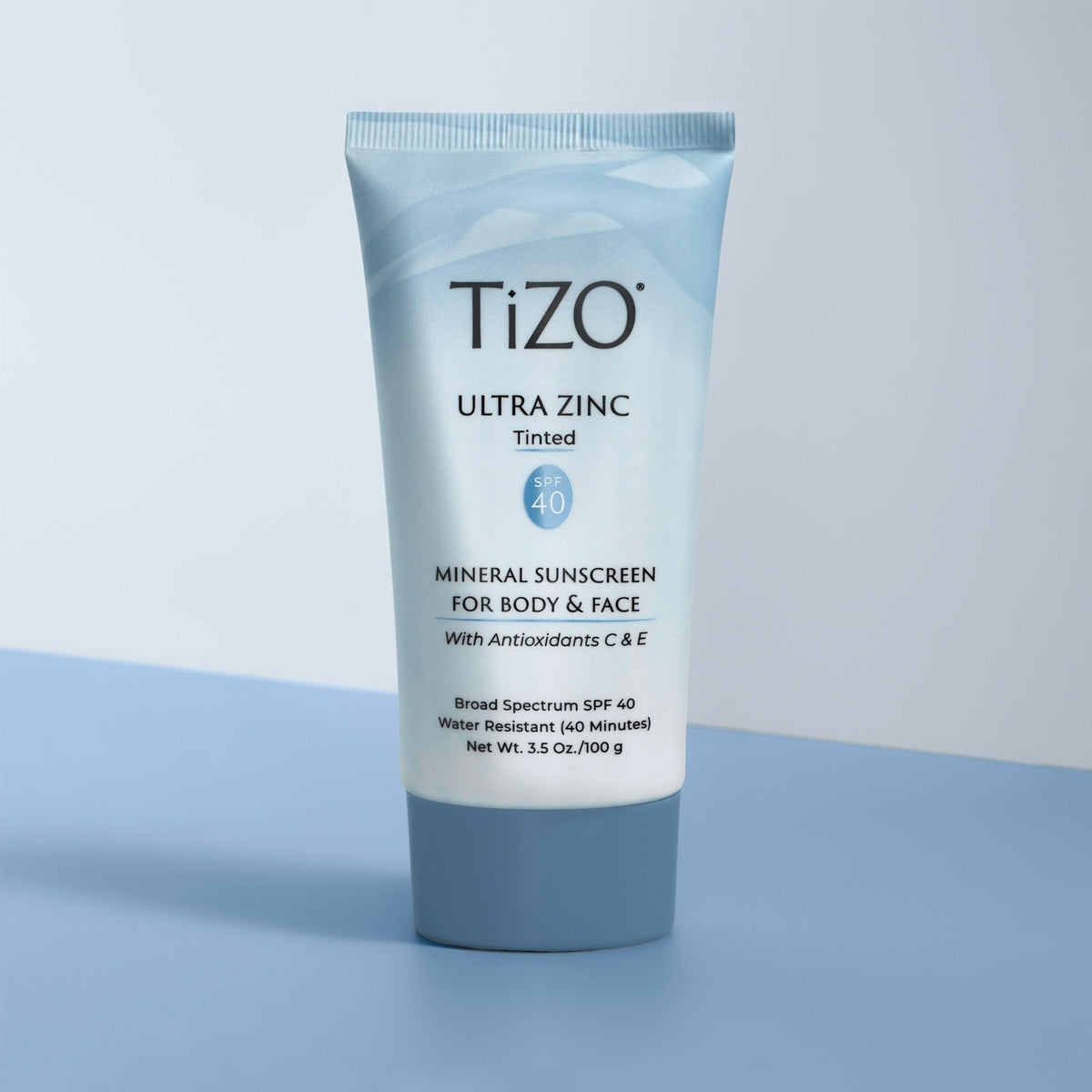 TIZO 3.5 oz tube alongside a coin to show portable size