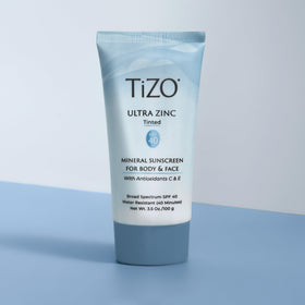 TIZO tube beside coin showing 3.5 oz size for travel convenience
