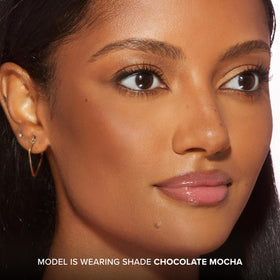 Too Faced bronzer stick held in hand showing compact size and portability