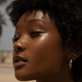 Tower 28 SuperDew on cheek lifestyle shot showing natural dewy glow benefit