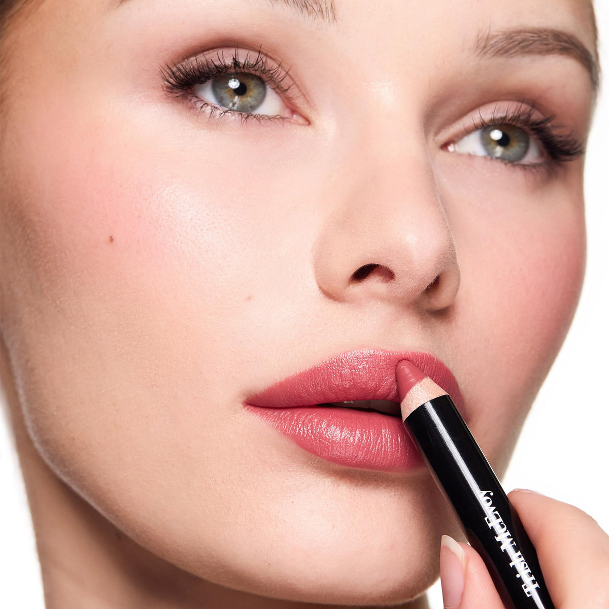 Trish McEvoy model applying crayon for a polished long-wearing pout