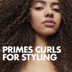 Applying Umberto Giannini curl jelly to damp hair with hands for controlled styling
