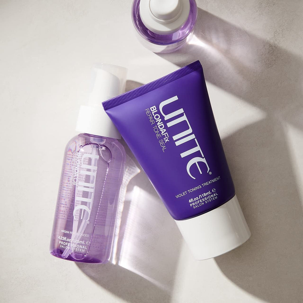 UNITE BLONDA Fix next to a hand to show 4 fl oz size for travel and salon use convenience