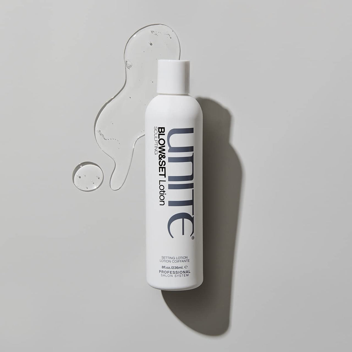 UNITE bottle held in hand for scale to show 8 fl oz size and portability