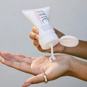 UNITE BOOSTA held in hand for size scale showing convenient 4 fl oz travel-friendly bottle